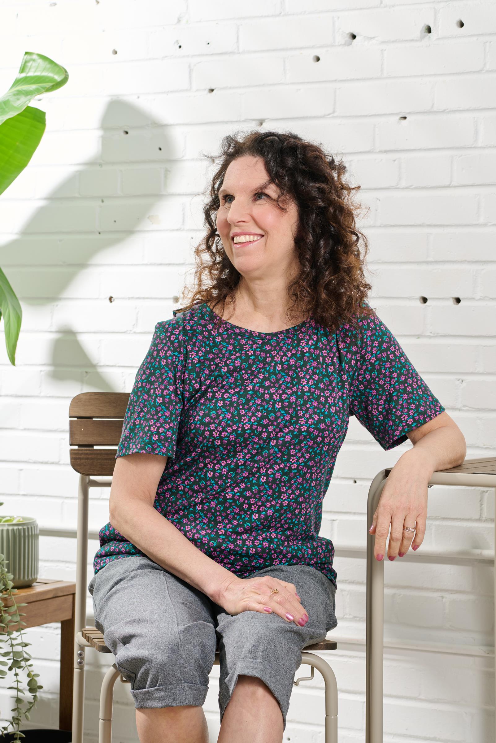This adaptive basic top is designed with short sleeves and a brushed knit for added comfort. It also features a beautiful flower pattern in mauve and emerald colors. Stay stylish and comfortable all day with this versatile top.colors
