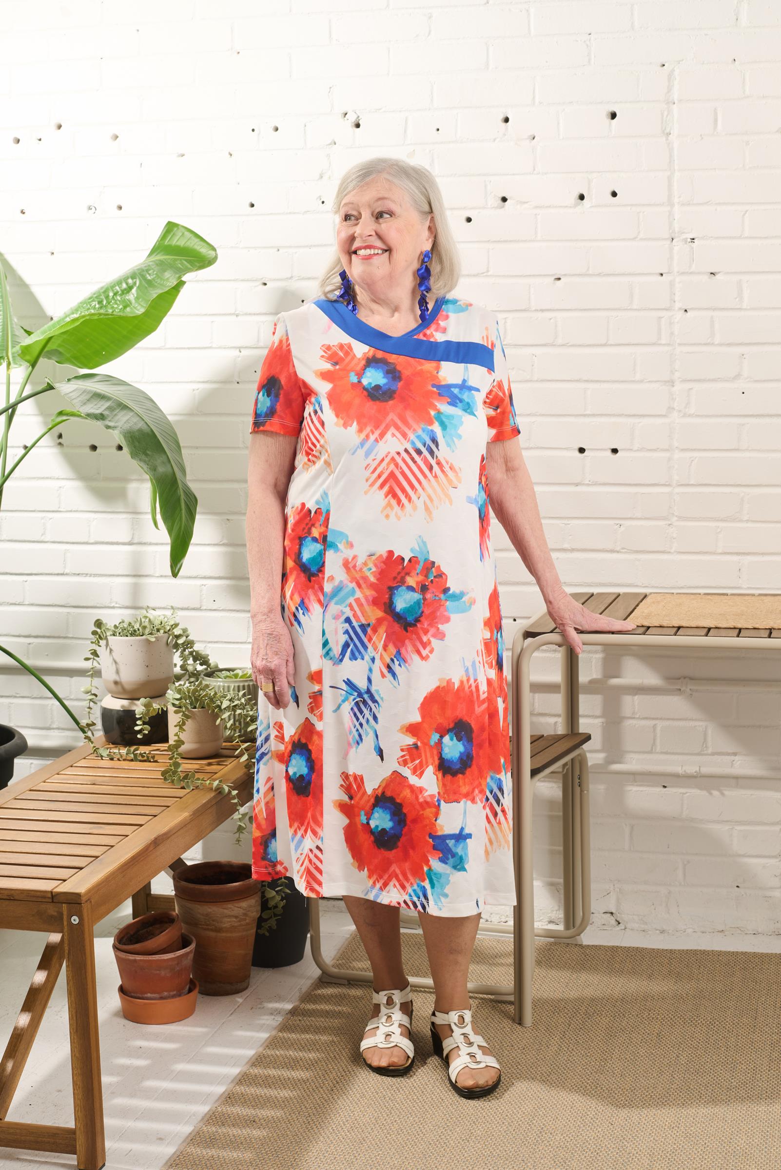 This adaptive dress features a stretch knit material and short sleeves for comfortable wear. The large opening and metal shoulder snaps make dressing and undressing easy for individuals with limited mobility. The daring flower design in white and orange a