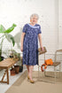 Easily dress in comfort and style with our adaptive dress. Designed with short sleeves and stretch knit, this dress offers a large opening and metal shoulder snaps for added convenience. Featuring a beautiful blue botanical pattern, it's perfect for any o